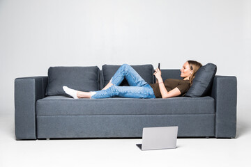 Beautiful happy woman on a white sofa making a phone call isolated