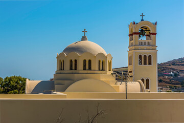 Wall Mural - A church bell tower and dome in the village of Emporio, Santorini in summertime