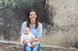 © Caro Telfer/Austockphoto - Happy mum and baby sitting outdoors on a rock