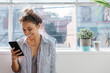 © Jodie Johnson/Austockphoto - Young creative female smiling and reading her phone at a studio window