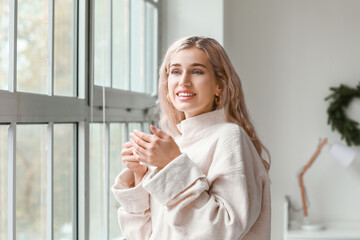 Sticker - Beautiful young woman in warm clothes drinking tea at home