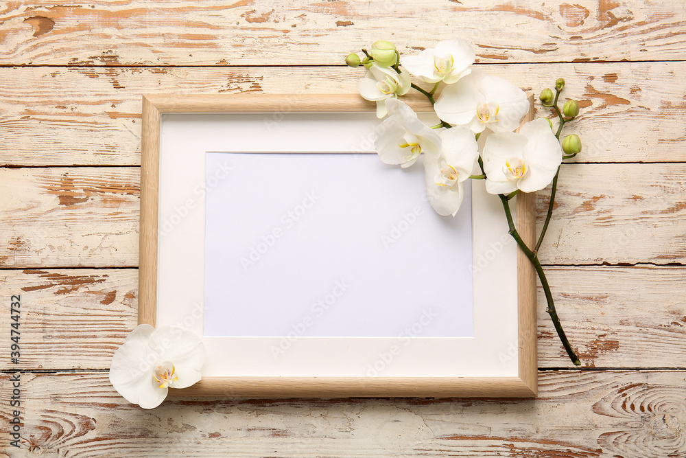 Beautiful orchid flowers and blank frame on wooden background