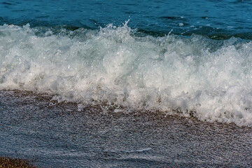 Wall Mural - Surf breaking on the seashore of the beach at Perissa, Santorini in summertime