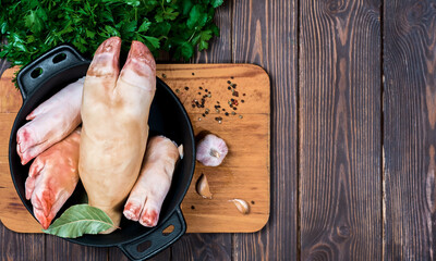 Set for making jelly in a saucepan - raw pork legs, beef legs, garlic and spices on a rustic wooden background. Layout with copy space. Ingredients for khash or jellied meat