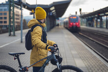 A Man In Winter Clothes, Waiting With His Bike, The Train. In The Background The Train That Is About To Arrive.