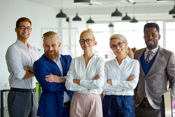 Wall Mural - portrait of successful multi-ethnic team looking at camera in the office, posing, young people have a good cooperation, stand with crossed hands smiling