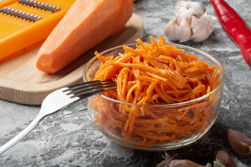 Carrot grated on a grater with thin straws. Korean carrot on a dark background.