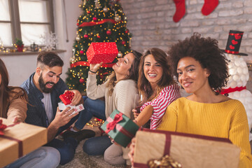 Friends exchanging and opening presents for Christmas