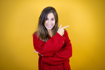 Young beautiful woman wearing red sweater over isolated yellow background smiling and pointing with hand and finger to the side