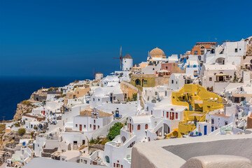 Wall Mural - Windmils, dome churches and dazzling white buildings in the village of Oia, Santorini in summertime