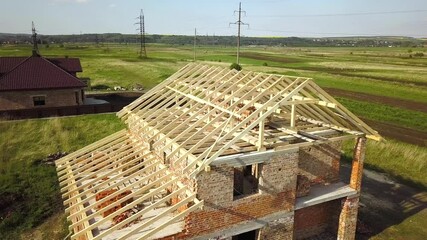 Wall Mural - Aerial view of unfinished brick house with wooden roof frame structure under construction.