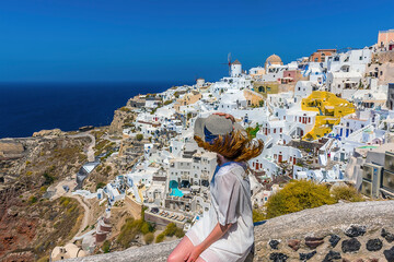 Wall Mural - Sitting on a wall admiring the village of Oia, Santorini in summertime