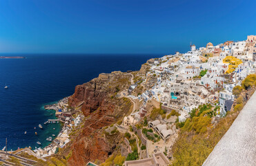 Wall Mural - A view of the northern edge of the village of Oia, Santorini with Amoudi Bay at the base of the cliffs in summertime