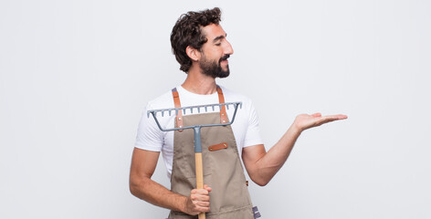 Wall Mural - young man feeling happy and smiling casually, looking to an object or concept held on the hand on the side