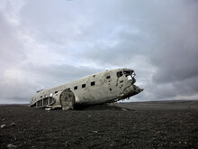 Abandoned Airplane On Field Against Cloudy Sky