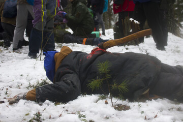 Ambulance drills in the winter forest. A supposedly drunk man with an ax in his back lies on the ground and resists. Reportage shooting from the scene