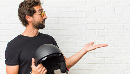 Wall Mural - young man feeling happy and smiling casually, looking to an object or concept held on the hand on the side