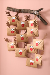 Wall Mural - Gifts in envelopes with deer faces hanging on pink wall. Christmas advent calendar