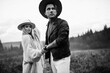 © shunevich - Handsome man and beautiful woman walking at the field, wearing hats, enjoy weekend together, loving husband gently hold a hand of adorable wife, fashionable couple concept