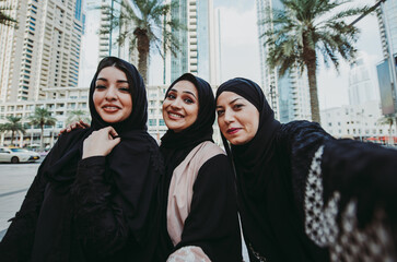 Wall Mural - Three women friends going out in Dubai. Girls wearing the united arab emirates traditional abaya