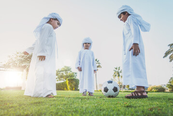 Wall Mural - Children playing together in Dubai in the park. Group of kids wearing traditional kandura white dress from arab emirates