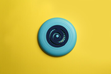 Poster - Blue plastic frisbee disk on yellow background, top view