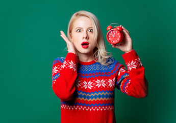 Wall Mural - Beautiful woman in Christmas sweater with alarm clock