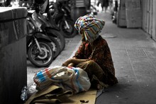 Male Beggar Sitting On Sidewalk