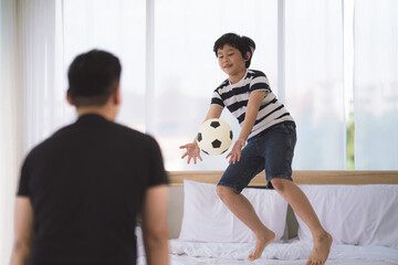 dad and son enjoy playing soccer football together in bedroom at home