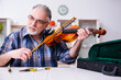 © Elnur - Senior male repairman repairing musical instruments at home