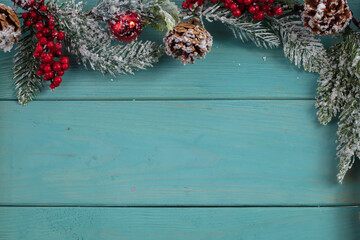 On a turquoise wood background, a decoration of a spruce branch and cones. Christmas background.