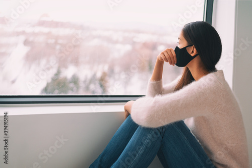 Cuadros en Lienzo Sad woman alone during coronavirus pandemic wearing face mask indoors at home for social distancing
