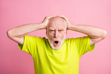 Portrait of unsatisfied aged guy hands on head open mouth yell loud lime clothing isolated on pink color background