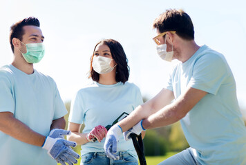 Canvas Print - volunteering, health and ecology concept - group of volunteers wearing face protective medical masks for protection from virus disease with garden tools in park