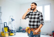 © Syda Productions - construction, communication and repair concept - happy smiling worker or builder calling on smartphone over room with building equipment background