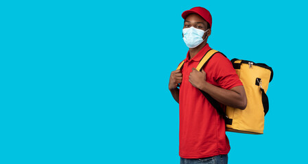 Wall Mural - African american delivery man in protective mask wearing thermo bag