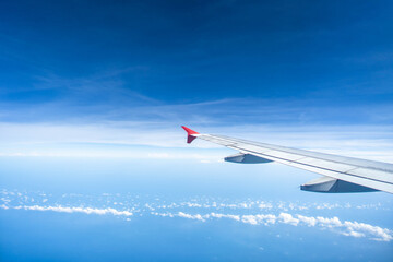 Airplane wing against beautiful tiny cloud and blue sky background.