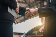 Midsection Of Business Colleagues Shaking Hands Against Car