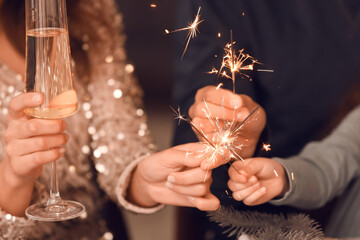 Happy family with sparklers and champagne celebrating Christmas at home, closeup