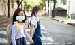 © Halfpoint - Small school girls with face mask outdoors in town, coronavirus concept.