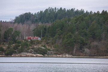 Red summer house by the ocean in the forest on a cloudy day