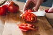 © Ritk - chef slicing tomato with ceramic knife on light wooden board. closeup.
