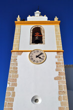 Traditional White Painted Church Tower With Clock & Bell Seen Against Blue Sky 