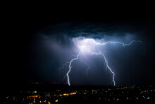 Lightning Over Cityscape Against Sky At Night