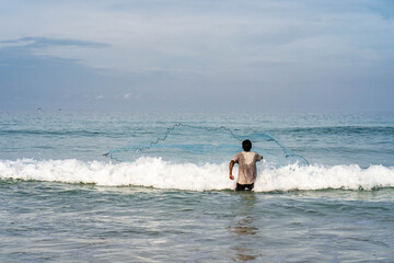 Fisherman cast a net at the beach.