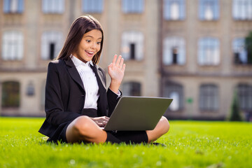 Poster - Photo of little pupil sit grass use laptop waving palm crossed legs wear black uniform urban city outdoors