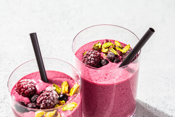 Wall Mural - Berry smoothie with nuts in glasses, light gray background, minimalism. Healthy detox drink concept.