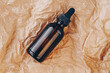 CBD oil bottle, hyaluronic acid tincture on creased cardboard. Serum with collagen and peptides on wrinkled crumpled paper. Beauty product mockup. Anti-age, body care concept. Flatlay, top view