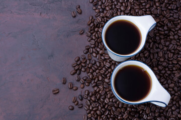 Fresh black coffee, a needle in a white coffee cup and fragrant roasted coffee beans, placed on a dark table Espresso coffee - Top view with copy space