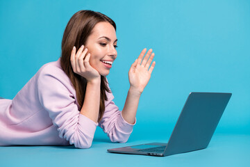 Poster - Profile side photo girl high school student lying floor remote study laptop have wifi connection seminar wave hand greet tutor wear violet lilac jumper sweater isolated blue color background